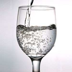 A glass filled with water showing bubbles as it is being poured. - International Hotel School