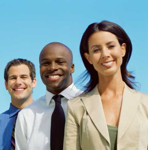Three smiling professionals standing in a row against a clear blue sky. - International Hotel School