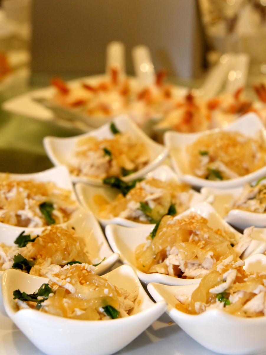 Small white bowls containing Asian-style chicken and vegetable dishes garnished with herbs and sesame seeds. - International Hotel School
