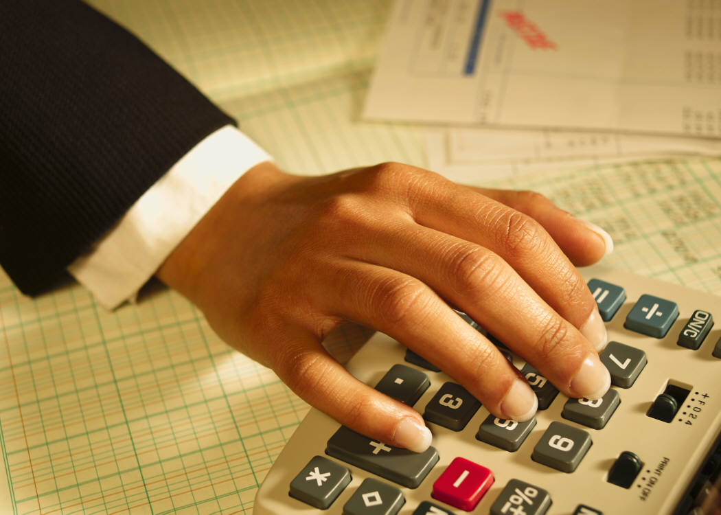 A hand resting on a calculator with a financial document in the background. - International Hotel School