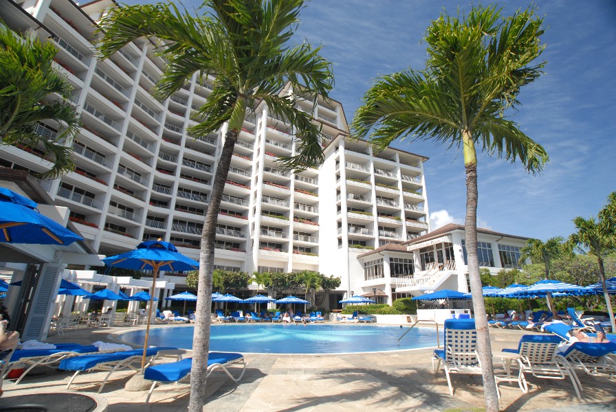 Resort hotel featuring a swimming pool surrounded by palm trees and lounge chairs. - International Hotel School