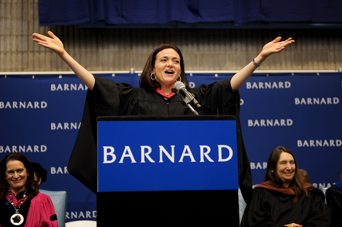 Sheryl Sandberg delivering a speech at Barnard College graduation ceremony with arms raised. - International Hotel School