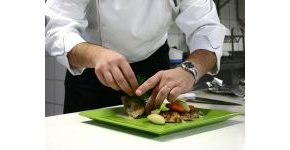Chef arranging food on a green plate in a kitchen setting. - International Hotel School