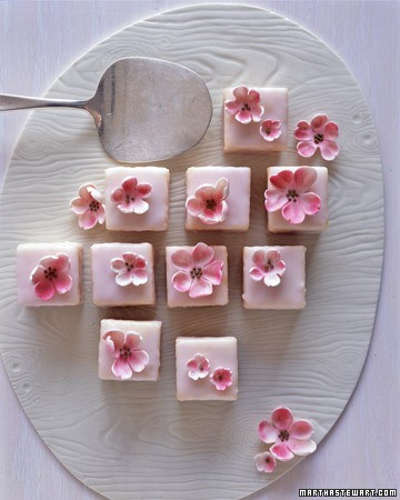 A collection of petits fours decorated with pink flowers arranged on a white platter. - International Hotel School