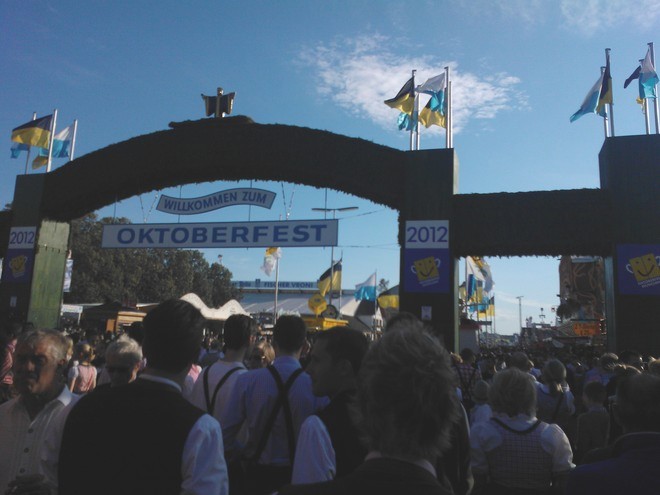 Entrance archway to Oktoberfest with flags and a welcoming sign in the background. - International Hotel School