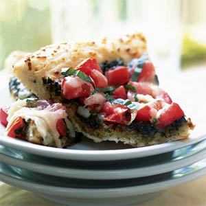 Slice of pizza topped with fresh tomatoes, basil, and melted cheese on a white plate. - International Hotel School