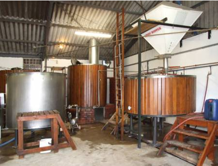 Interior view of brewing equipment including large metal and wooden tanks in a facility. - International Hotel School