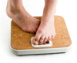 Person's feet standing on a digital bathroom scale with a cork surface. - International Hotel School