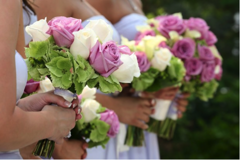 Three bridal bouquets featuring pink and white roses with green accents held by bridesmaids. - International Hotel School