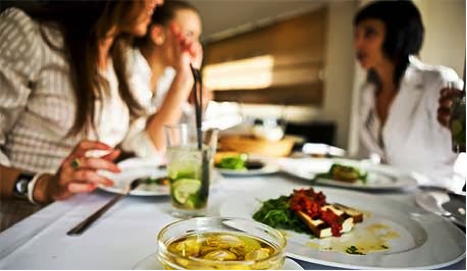 Table set with plates of food and drinks, featuring a glass of yellow beverage and dishes with various ingredients. - International Hotel School
