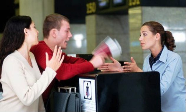 Two individuals interacting with a hotel receptionist at a front desk. - International Hotel School