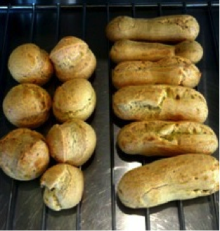 Baked cream puffs and eclairs arranged on a cooling rack. - International Hotel School