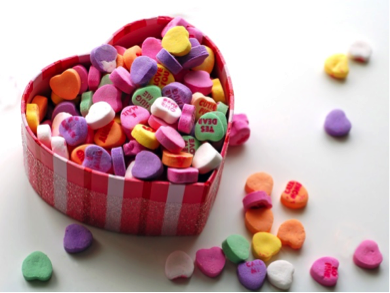 Heart-shaped box filled with colorful conversation heart candies in various messages and colors. - International Hotel School