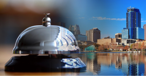 A polished hotel reception bell in the foreground with a city skyline in the background. - International Hotel School