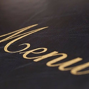 Close-up of a restaurant menu cover with the word 'Menu' embossed in gold lettering. - International Hotel School