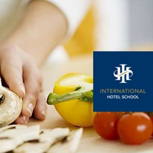 Person preparing food with vegetables on a cutting board in a kitchen setting. - International Hotel School