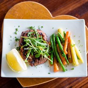 Grilled meat served with a side of green beans, carrots, and a lemon wedge on a white plate. - International Hotel School