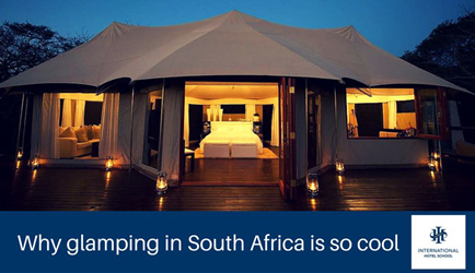 A spacious glamping tent featuring a large bed and warm lighting in South Africa. - International Hotel School