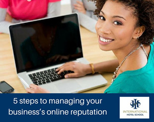 Woman smiling while using a laptop to manage online reputation, with a smartphone nearby. - International Hotel School