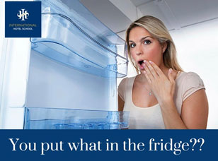 A woman with a surprised expression looking into an open refrigerator with empty shelves. - International Hotel School