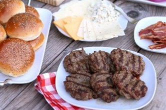 Grilled burger patties arranged on a plate with buns and cheese slices nearby. - International Hotel School