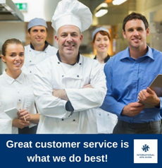 A group of hospitality professionals, including a chef and staff, posing together in a kitchen setting. - International Hotel School
