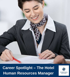 A woman in a business suit reviewing documents with a pen in hand, representing a hotel human resources manager. - International Hotel School
