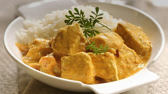 A bowl of chicken korma served with white rice and garnished with fresh herbs. - International Hotel School