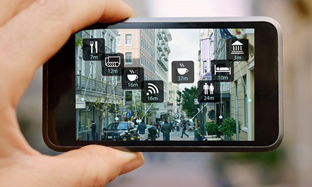 A smartphone held in hand showing augmented reality navigation with various icons for nearby locations. - International Hotel School