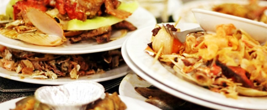Multiple plates stacked with different types of food, including seafood and vegetables. - International Hotel School