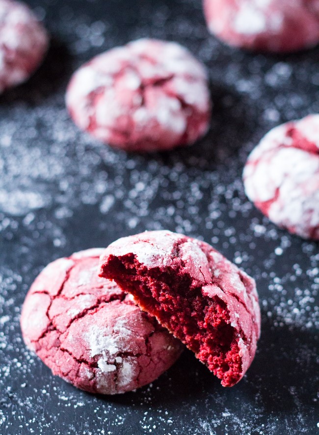 Red velvet cookies with a cracked surface and powdered sugar coating, one cookie partially bitten into. - International Hotel School