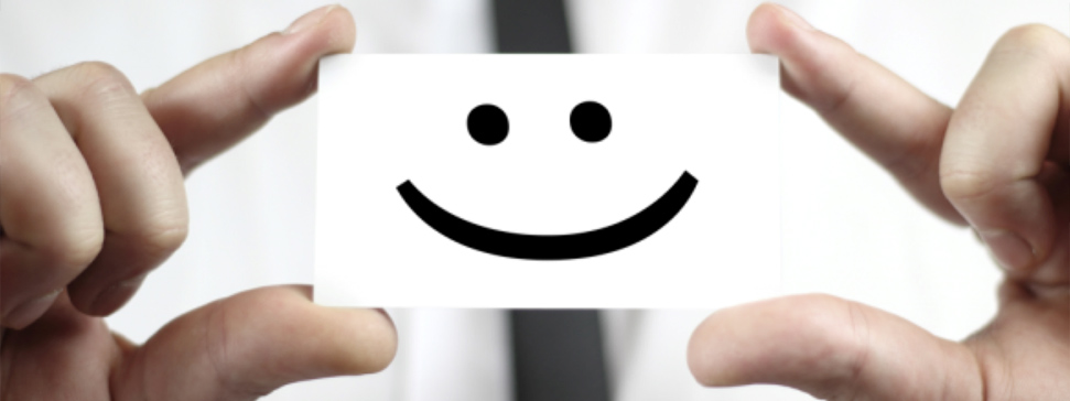 Hands holding a card displaying a simple smiley face graphic. - International Hotel School