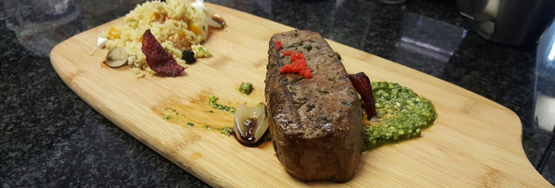 Grilled steak served on a wooden board with sides of sauce and rice. - International Hotel School