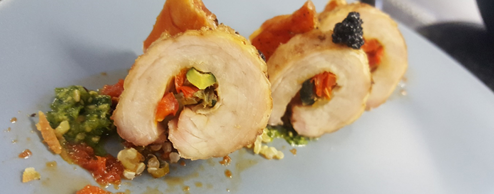 Three slices of pork belly roulade with colorful vegetable filling on a blue plate. - International Hotel School