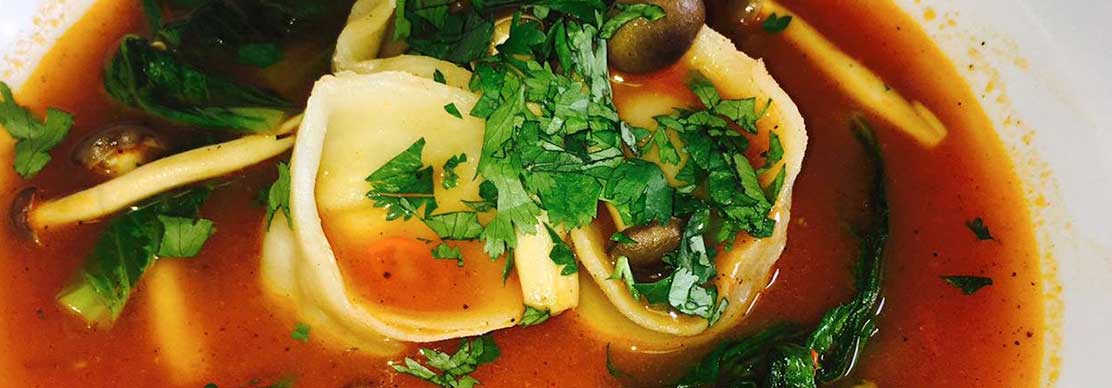 Bowl of dim sum consomme soup with herbs and vegetables in a rich broth. - International Hotel School
