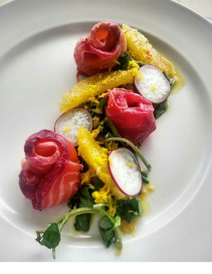 Salmon gravlax arranged with citrus segments and radish slices on a white plate. - International Hotel School