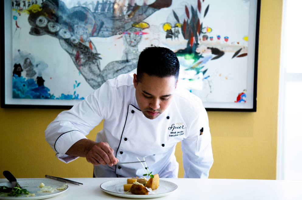 Chef carefully plating a dish with attention to detail in a culinary setting. - International Hotel School