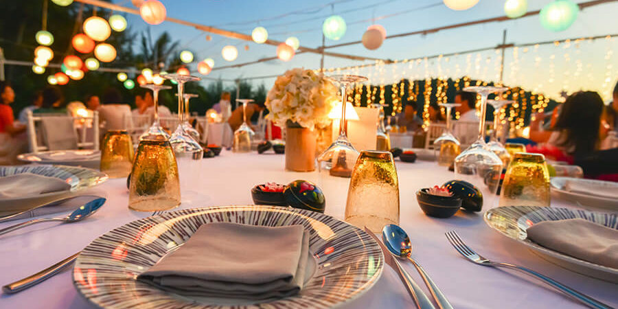 A beautifully arranged dining table with plates, glasses, and decorative lighting in the background. - International Hotel School