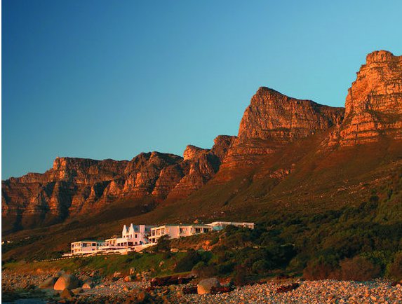 12 Apostles Hotel situated near a mountain range during sunset. - International Hotel School