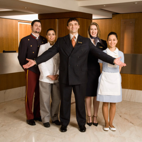 Group of hotel staff members posing together in a lobby setting with a smiling manager in front. - International Hotel School