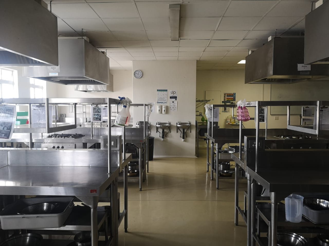 Interior view of a commercial kitchen with stainless steel surfaces and cooking equipment. - International Hotel School