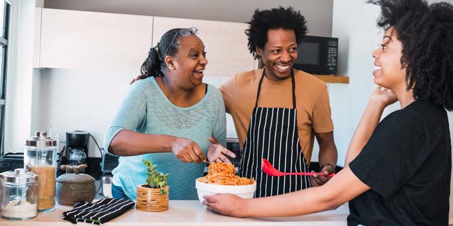A family cooking together in a modern kitchen, sharing a meal preparation experience. - International Hotel School