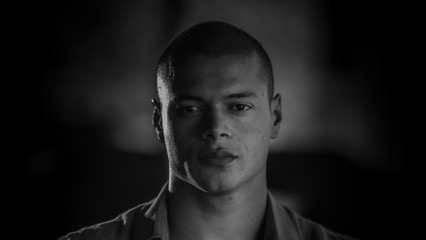 Black and white portrait of a young man with a shaved head and serious expression. - International Hotel School