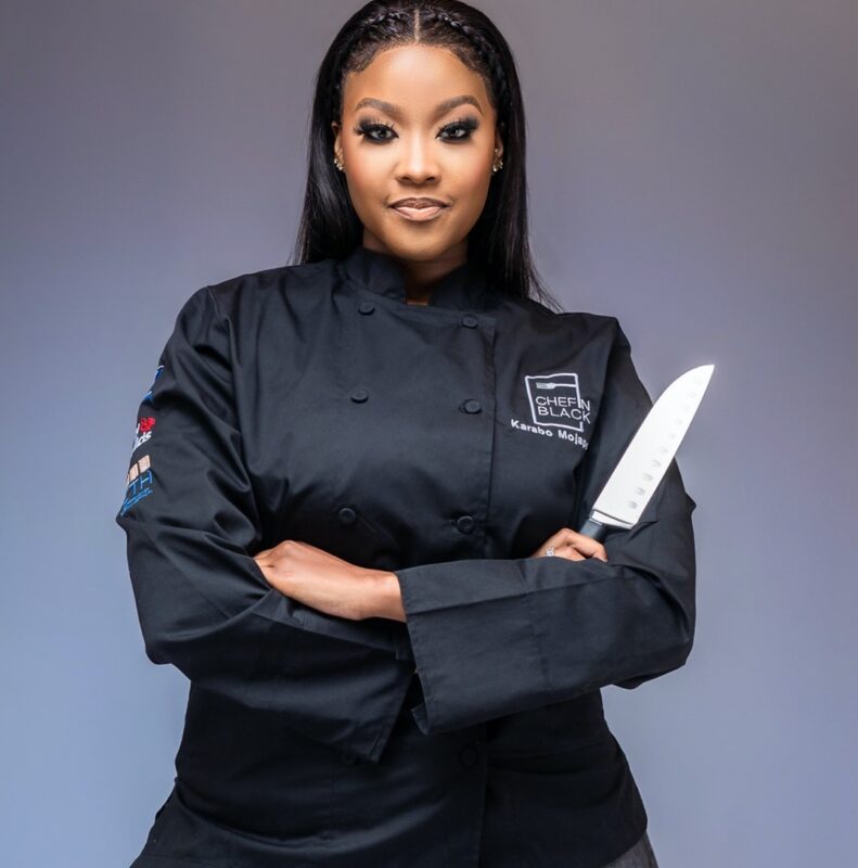 Chef Karabo wearing a black culinary uniform and holding a knife, posing confidently. - International Hotel School